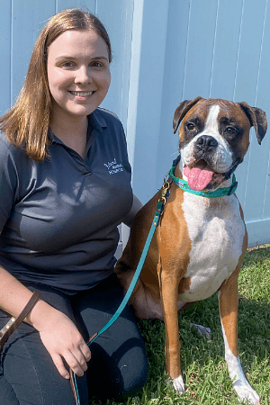 Abby female with sandy blonde hair kneeling beside brown and white boxer