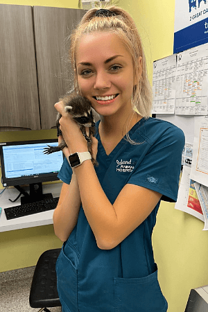 Elizabeth Breitigan Female with long blonde hair in a pony tail holding a baby raccoon