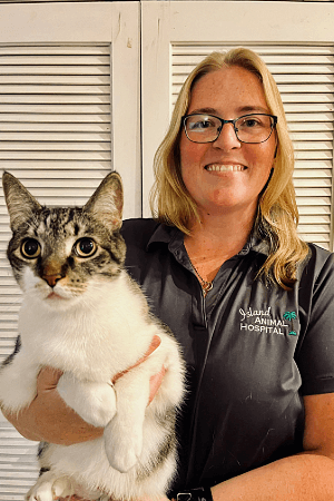Lauren Holly female with blonde hair and glasses holding a white cat with gray stripped head