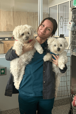 female holding 2 small white dogs