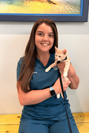 Emma Kahrs female wearing teal scrubs holding a small orange and white cat